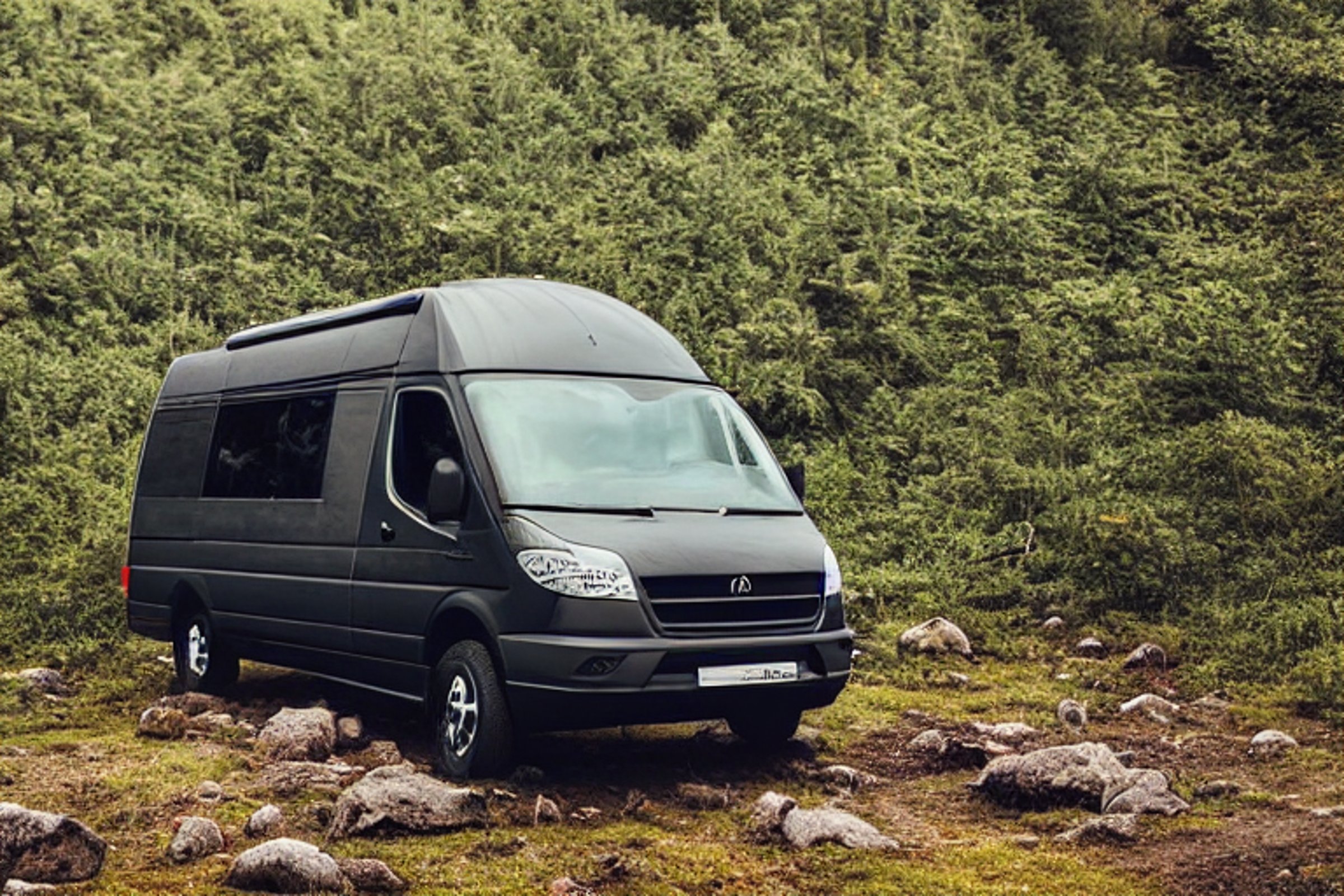 A black camper van rests on a muddy campsite near the beach as rain falls at dusk. A glowing tent, a backpack, and a winding hiking path add a cozy outdoor feel, with a mountain rising in the distance.