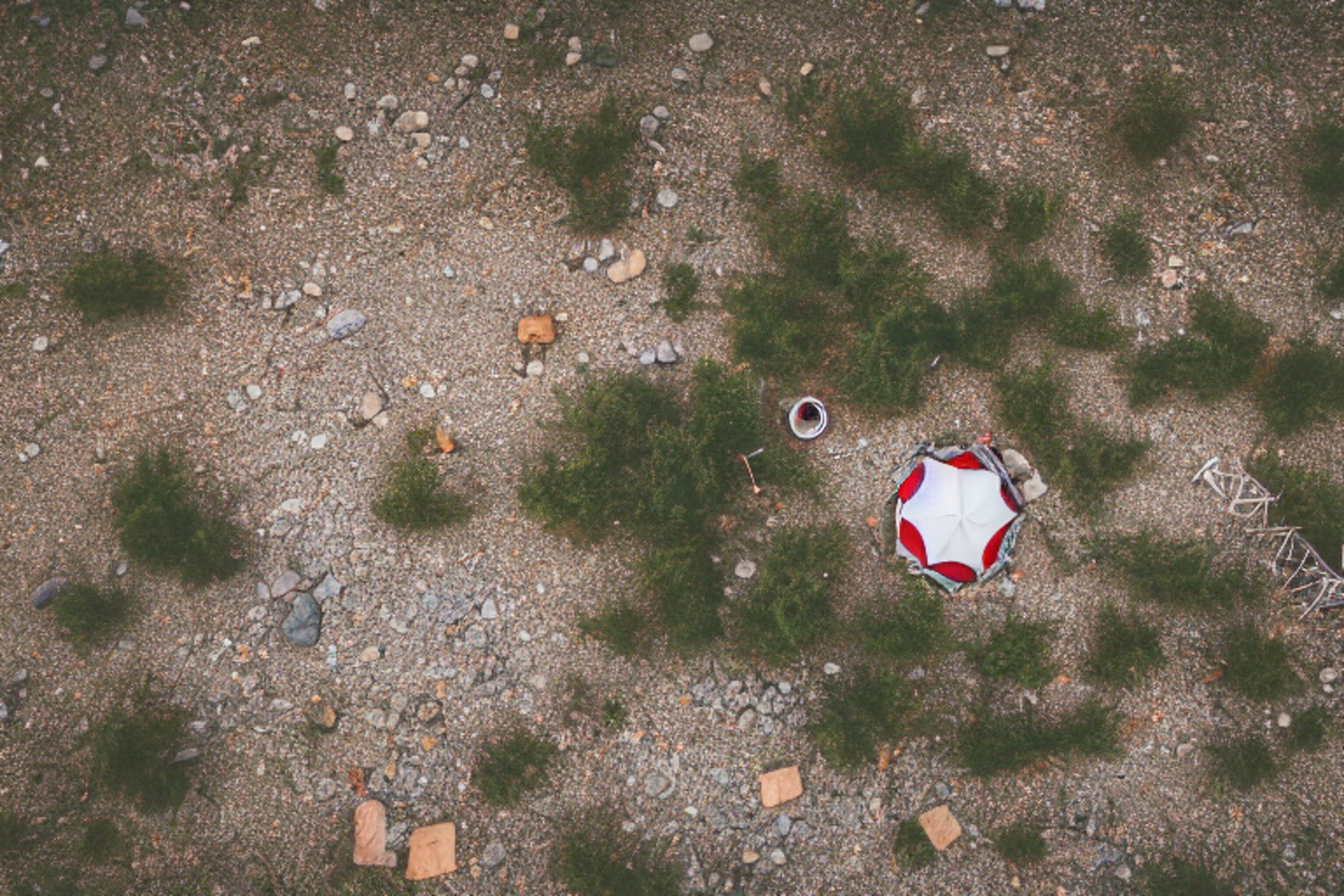 A red and white tent glows beside a paved campsite in the New Mexico desert. A crackling campfire warms the quiet night, while logs and stones sit on the dusty ground. Stars peek through the cloudy sky above.