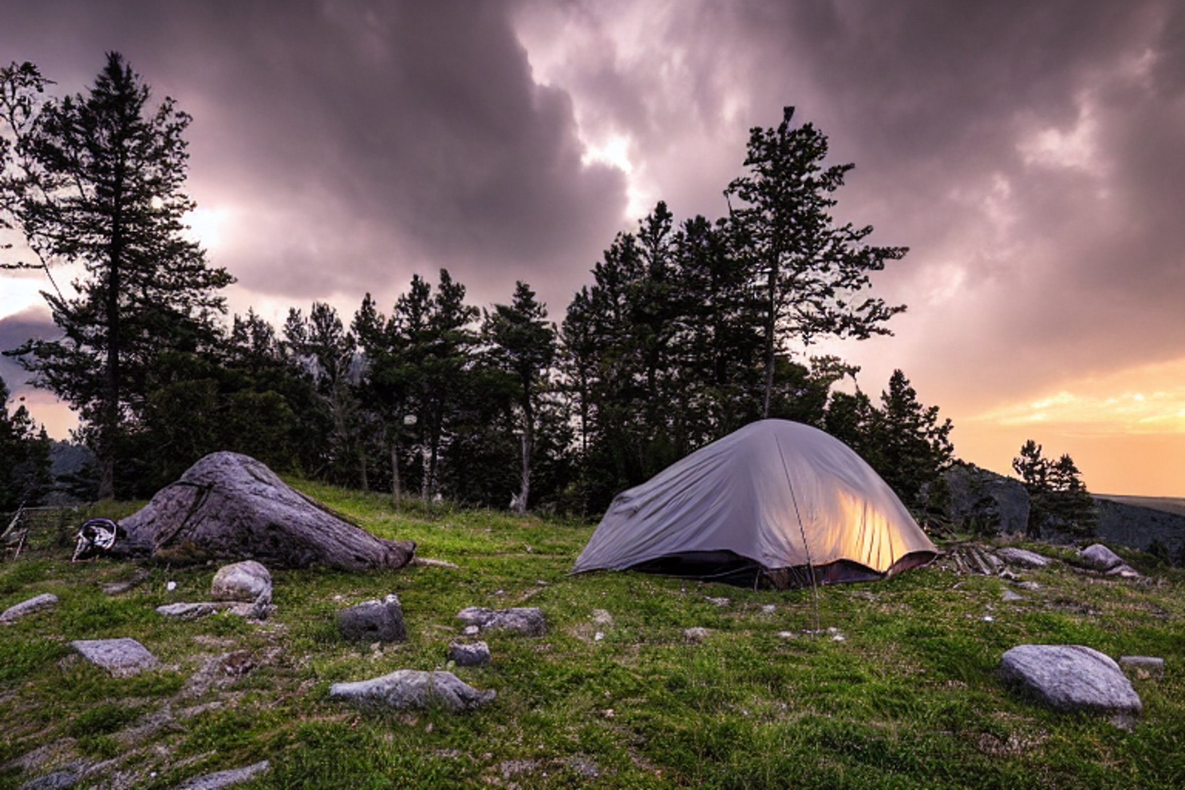 A black tent sits on a dirt campsite high on a mountain. Large stone slabs and trees surround a warm campfire, while rolling hills stretch beneath a stormy sunset sky.