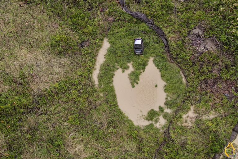 A cozy camper van rests on a sunny beach campsite near the ocean. Large bushes surround the dirt clearing, with a hiking path and backpack nearby. A campfire adds a warm touch to the peaceful outdoor setting.