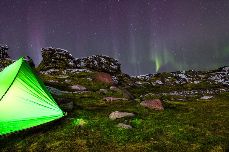 A green camo tent glows softly on a rainy campsite in Norway. Above it, bright northern lights dance across the night sky, while boulders and stone slabs surround the gravel ground.