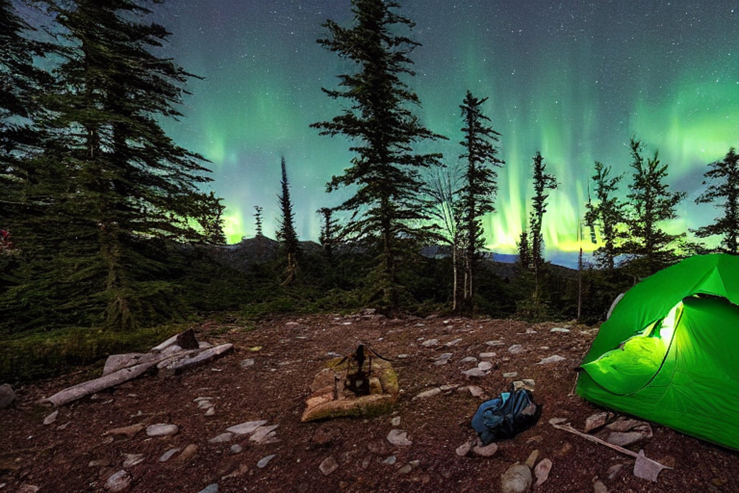 Two green camo tents sit beside a warm campfire in a snowy forest clearing. Bright northern lights glow above the ferns and winding hiking path, while a lantern lights the ground and the moon shines in the distance.