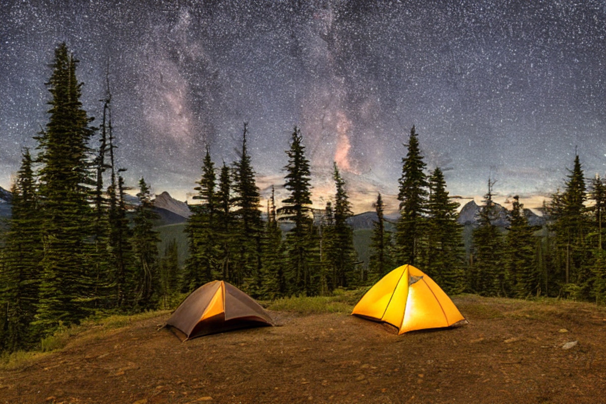 A brown tent rests on a dirt clearing in Glacier National Park, surrounded by tall trees and rolling hills. A warm campfire glows under the starry night sky as hikers enjoy the quiet, rugged campsite.